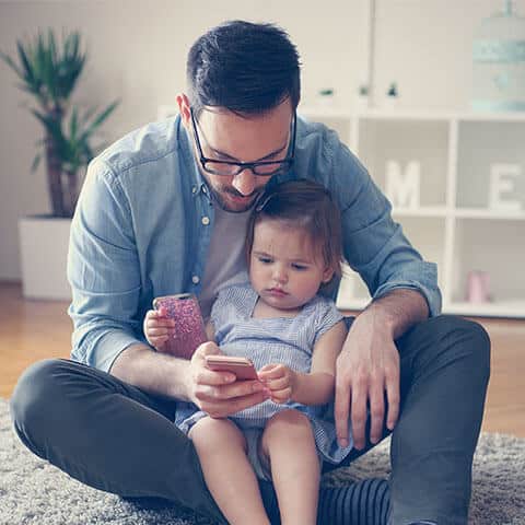 Kinderbetreuung suchen mit LITTLE BIRD Vater mit Kleinkind schauen zusammen aufs Handy